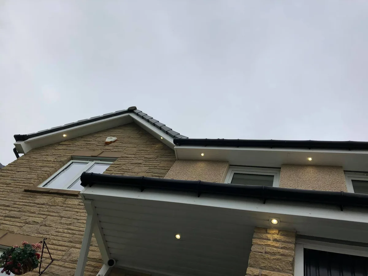 Finished: downlights lit along the eaves and over the porch canopy of a new-build house in Dargavel Village